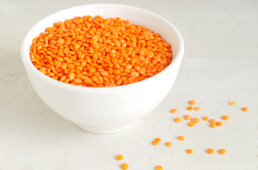 Orange lentils in a white bowl on a light background. The concept of proper nutrition. Vegan and vegetarian food. Horizontal orientation. Copy space.