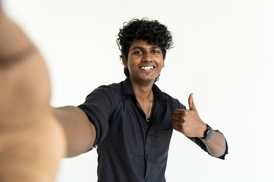 Indian man doing selfie shot pov on mobile phone show thumb up isolated on grey background studio.