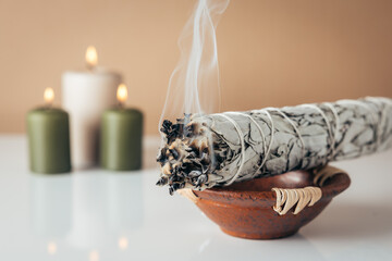 White sage and burning candles in background