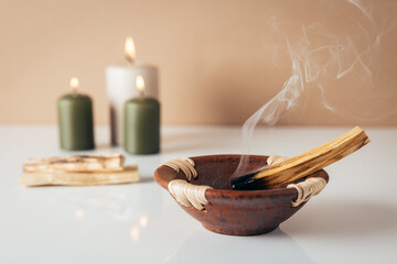 Palo santo burning stick and candles in background - 678086455