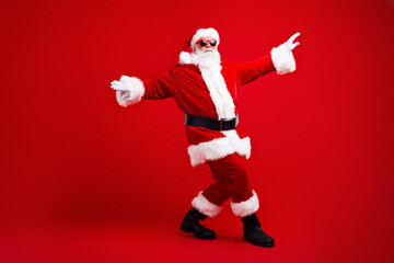 Fototapeta na wymiar Full length photo of good mood santa claus in sunglass celebrate new year dancing at cristmas party isolated on red color background
