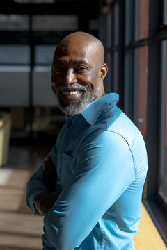 Portrait of happy senior bald african american casual businessman with beard smiling at office