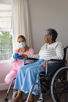 Caucasian female nurse in face mask using epi pen on senior african american woman