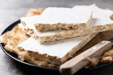 Traditional Christmas sweet, pieces of delicious almond nougat on wooden table	
