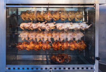 A stack of grilled chicken on a skewer fried in a commercial oven. Chicken roasting in commercial rotisserie oven
