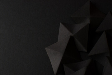 Black abstract geometric shapes on dark background, top view, copy space