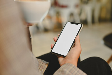 Closeup young businesswoman drinking coffee and checking social media on mobile phone