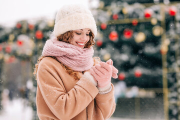 A beautiful young girl shakes snow off her mittens. A woman poses in front of a New Year tree.