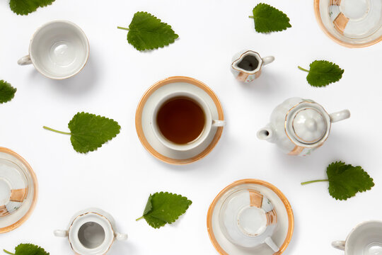 Top view of a tea set with fresh lemon balm leaves on a white background