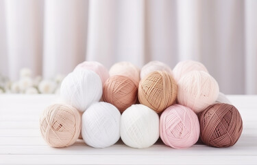 Fototapeta na wymiar White, beige, pink balls of thread and metal knitting needles lying on a white wooden table soft light