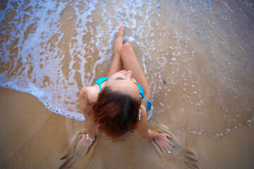 A beautiful girl in a bikini on a wild beach, bathing in the clear waves of the warm sea. a heavenly place and a beautiful model.