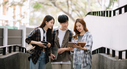 Asian Students are studying the campus park. Young people are spending time together. Reading book, working with laptop, tablet while sitting on stairs