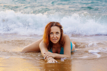 A beautiful girl in a bikini on a wild beach, bathing in the clear waves of the warm sea. a...