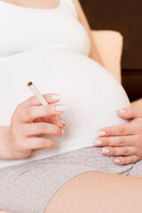 Obraz na płótnie Canvas Pregnant woman smoking cigarette at home in bed