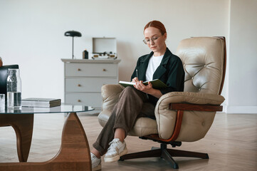 Woman psychologist in formal clothes is with notepad indoors