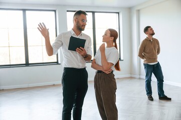 Fototapeta premium Realtor shows an apartment to a young couple