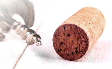 Wine cork and corkscrew on white surface on soft sunlight