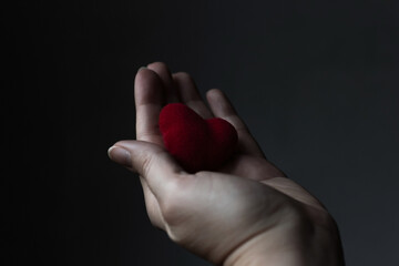 Red heart in woman's hand on grey background. The concept of charity, love, donate and helping...