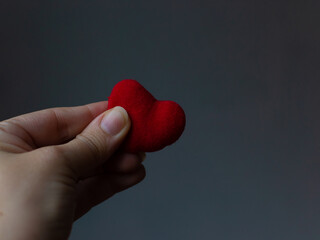 Red heart in woman's hand on grey background. The concept of charity, love, donate and helping...
