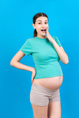 Fototapeta na wymiar Young surprise or shocked woman pregnant isolated colored background. expression female