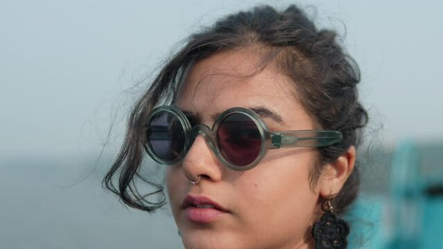Close-up shot of a fashionable young Indian woman. Adorned with stylish sunglasses and a nose piercing.