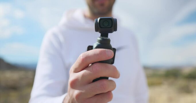 Vlogger showing modern DJI Osmo Pocket 3 stabilized intelligent tracking mobile gimbal camera for creative videography