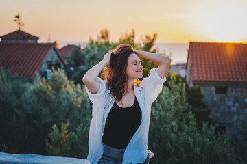 Young cheerful woman enjoying a beautiful moment at sunset. Joy of life concept
