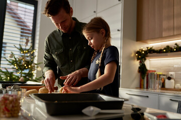 Caucasian father  and daughter making gingerbreads in domestic kitchen