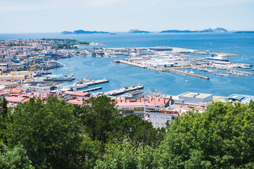Fototapeta na wymiar The view from the hill in Parque Monte del Castro, park located on a hill in Vigo, the biggest city in Galicia Region, in the North of Spain. View of the sea, harbour and docks, selective focus