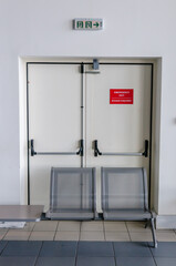 Emergency exit fire doors blocked by seating in a Greek airport making emergency evacuation impossible.