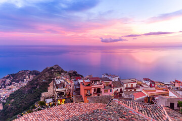 sceniv view from a high mountain town to amazing landscape of sea coast, roofs in vintage style of Italy and beautiful colorful sunset or sunrise cloudy sky