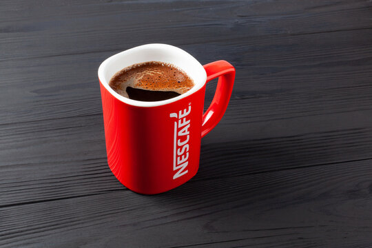 A red Nescafe cup of strong coffee on black table. Red mug with coffee Nescafe.