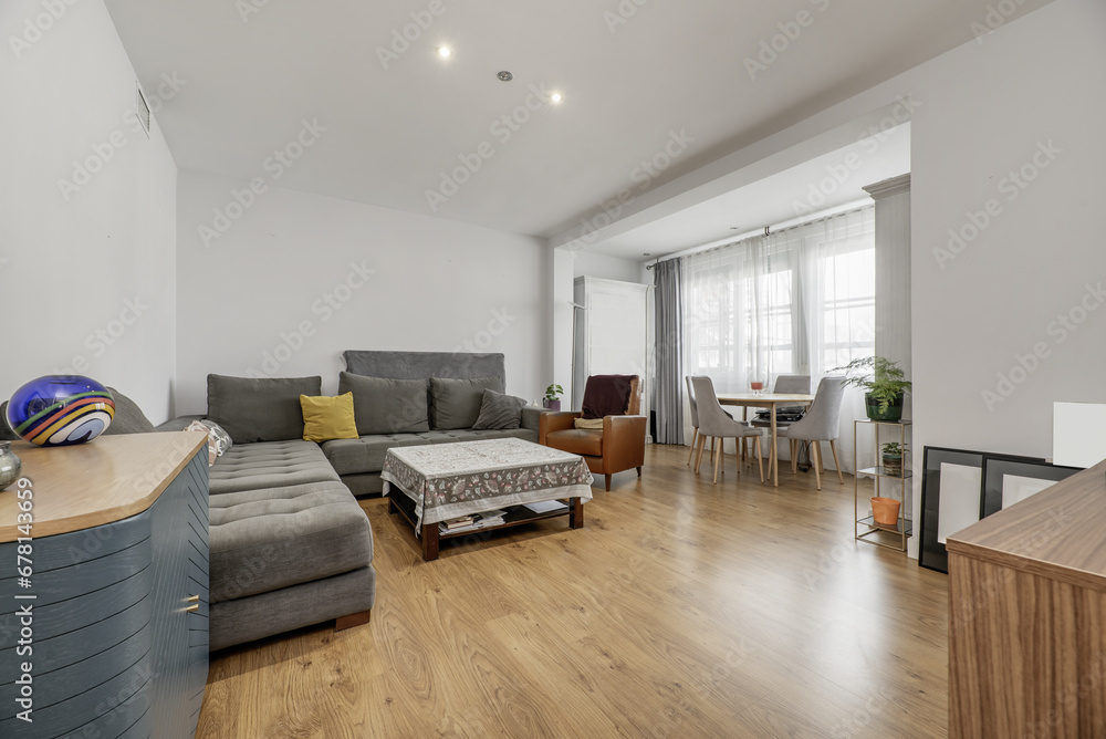 Wall mural a spacious living room with a corner sofa upholstered in gray fabric, a circular wooden dining table