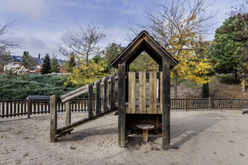 Fototapeta na wymiar A wooden structure with an access walkway to a slide in an urban children's play park