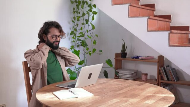 Man working with laptop from home stretching back to correct posture. Overworked Computer Concept. High quality 4k footage