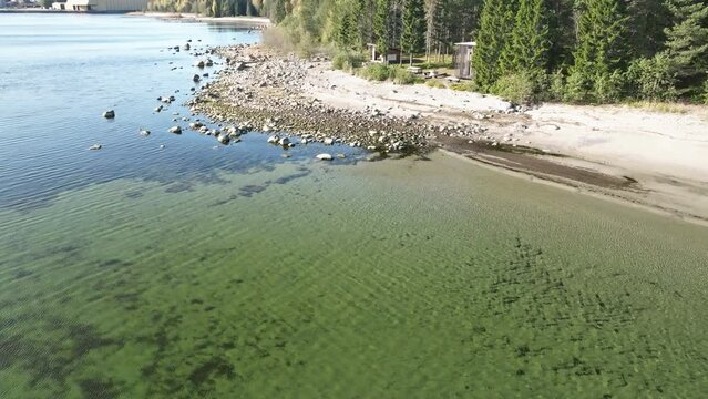 Stony Foreshore With Crystal Clear Water On A Calm Beach In Sweden. Low Aerial Shot