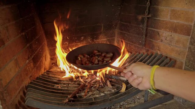 Close Up Shot of chef's Hand Cooking Chestnuts on the direct Fire of the Grill