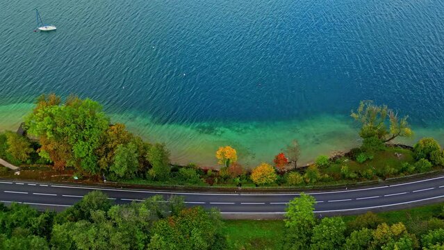 Aerial overview of a car on a road on the coast of lake Attersee, fall in Austria