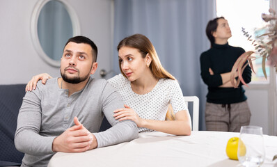 Worried young woman embracing, comforting and soothing her upset stressed husband while their...