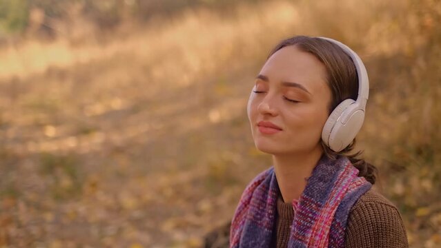 woman in headphones listens to music in the park, enjoys music in the forest, young Caucasian woman goes hiking, girl with a tourist backpack in the forest, My Real Holiday, MyRealHoliday