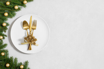 Festive table setting with Christmas decor and utensils, gold accessories on a white background....