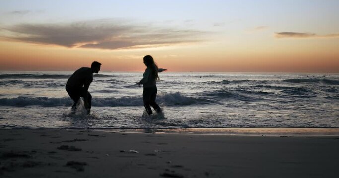 Couple are running into ocean, silhouette and sunset with fun, game and bonding with love on romantic date outdoor. Man, woman in healthy relationship with adventure, beach and energy with freedom