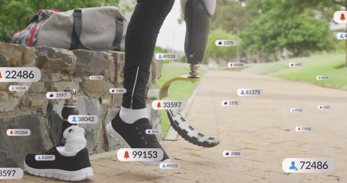 Animation of social media icons against low section of man adjusting his prosthetic leg at the park