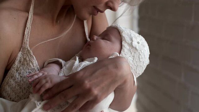 Mom Rocks Her Newborn Baby In Her Arms. The Baby Is Sleeping In His Mother's Arms.