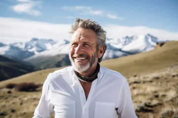 Portrait of a cheerful man in his 50s wearing a classic white shirt against a snowy mountain range. AI Generation