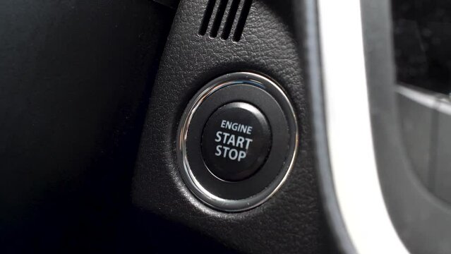 Man clicking start stop engine button in a car, keyless start