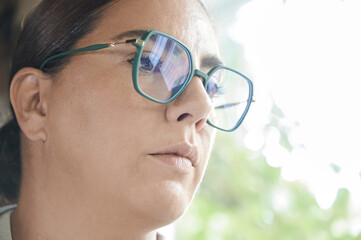 Young brunette woman wearing glasses with blue filter to avoid eye strain while using the computer.