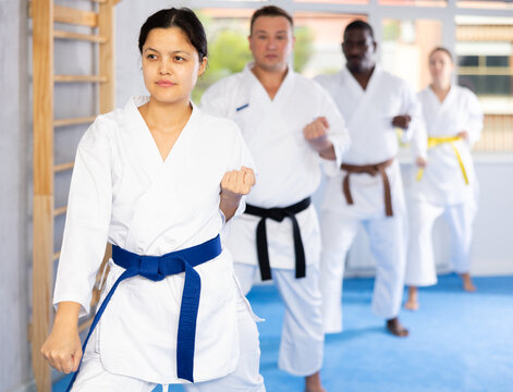 Kata karate teacher conducts classes and performs movements and fighting techniques together with cosmopolite students to prepare them for competitions.