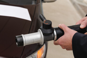 A man holds the high pressure (350 bar) nozzel at a hydrogen fuel filling pump station.