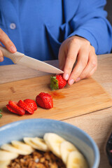 Woman cuts strawberries. Cooking breakfast.